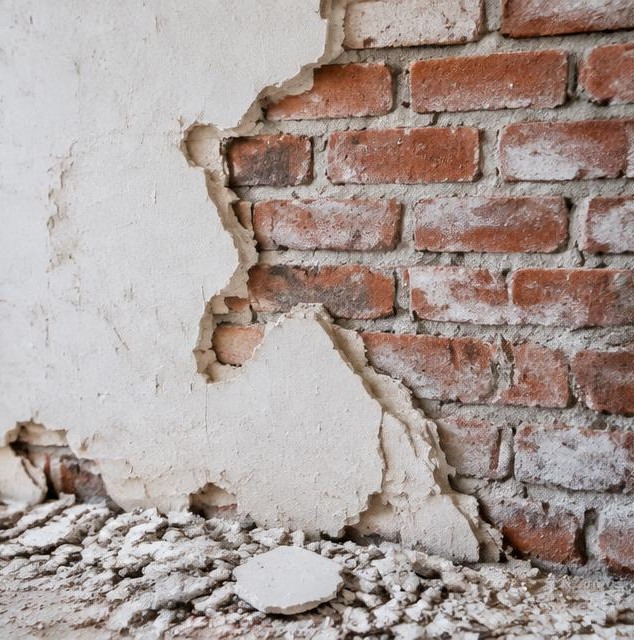 Gedeeltelijk afgekapt pleisterwerk op een bakstenen muur